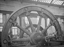 Flywheel; the hub and spokes cast in two halves, bolted at the hub with the rim assembled from ten castings. These are bolted to the spokes, held together by shrinking rings in the grooves.[78]