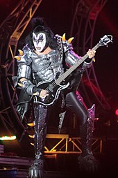 Gene Simmons, le bassiste du groupe, sur scène, en costume, et avec son maquillage blanc et noir.