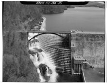 View of spillway looking upstream perpendicular to dam axis. White water flowing down spillway and calm water upstream from the dam.