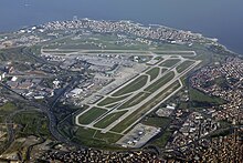 An aerial view of an airport with three runways and several taxiways arranged around a terminal