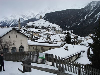 in winter with snow on roofs, view to mountains in Sesvenna group