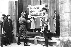 Fixació de cartells indicant el boicot a les botigues jueves l'any 1933