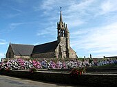 L'église de Gurunhuel derrière un mur couvert d'hortensias.