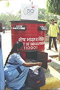 A Postwomen Group "D" employee of Department of Posts in her new uniform - (light blue colour Saree with dark blue border and pallau on it) collects Mail from the letter box, in New Delhi on October 1, 2004.jpg