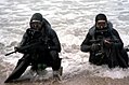 SEALs con trajes de buzo emergiendo del océano.