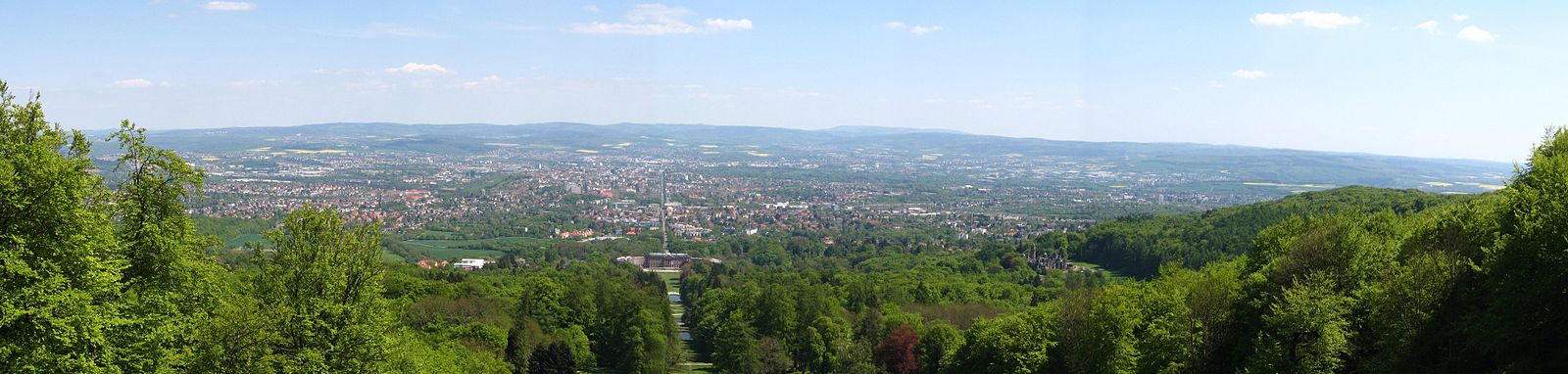 Bekanntes Motiv in Nordhessen: Blick vom Fuß des Herkules über den Bergpark Wilhelmshöhe auf Kassel: In der Bildmitte ist die zentrale Parkachse mit Schloss Wilhelmshöhe zu sehen, die ihre Verlängerung in der Wilhelmshöher Allee findet. Rechts im Bild ist auf halber Höhe die Löwenburg zu erkennen.