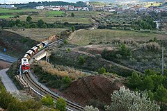 Un curt tren de vagons buits de potassa amb la vila de Callús al fons.