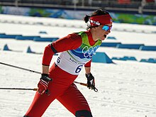 Photographie d'une femme faisant du ski de fond en combinaison rouge et portant le numéro 6.