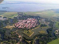 De stervormige vesting Naarden vanuit de lucht. Op de achtergrond het Gooimeer met links het eilandje De Schelp (2006). De vesting met omliggend gebied is sinds 1985 een beschermd stadsgezicht.