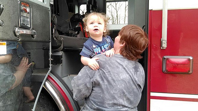 My grandson DJ at 2 yrs old getting to sit in fire truck for first time. My friend Mary is helping him