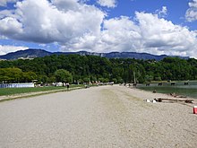 Vue en couleurs sur une plage en bordure d'une étendue d'eau.