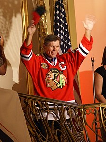 Stan Mikita dans le maillot rouge des Blackhawks qui salut la foule depuis un balcon