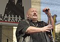 Der Sänger Jürgen Zeltinger in einem schwarzen Umhang mit einem Mikrofon auf der Bühne anlässlich der Demonstration „Köln stellt sich quer“ 2008, im Hintergrund das Veranstaltungslogo mit stilisiertem Dom und Menschenkette