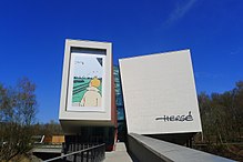 Vue d'ensemble du musée de style contemporain, une vignette d'un album montrant Tintin de dos et la signature d'Hergé étant visibles sur la façade.