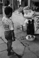 ペコちゃん人形とペコちゃんの持っているミルキーを狙う戦災孤児（1950年）