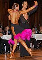 Image 11Latin dancers in their costumes. The woman is wearing backless dress with deep slits on its lower portion, while the man is wearing a shirt with top buttons open. (from Fashion)