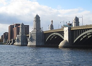 A bridge with metal arches and stone piers over a wide river