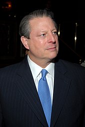 A man wearing a black suit with a blue tie