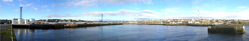 Wick Harbour, Scotland, with the ex-RMAS Fleet Tender Ilchester and windmill blades to the left and the river in the center.