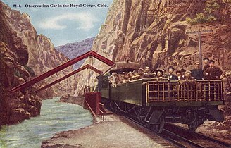 Open observation car at the Hanging Bridge of the Royal Gorge on the Denver and Rio Grande Western Railroad in 1918. The enclosed observation car is directly in front of it.