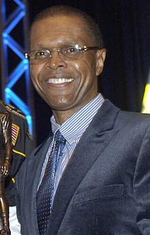 Gale Sayers poses for a picture while holding a trophy.