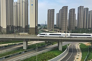 Urbanisation dense, architecture de grande hauteur (25-30 étages). Voies rapides. LGV Pékin - Canton, 2 298 km à 300 km/h, ici/ Zhengzhou, ligne ouverte en 01-2013.