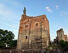 Photographie en couleurs d'un donjon surmonté d'une statue.