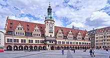 Grand bâtiment sur une grande place avec une rangée d'arcades au rez-de-chaussée.