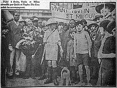 Photographie de presse en noir et blanc montrant de jeunes garçons entourés par une foule nombreuse. Sur une banderole est écrit "vivent Tintin et Milou"