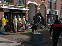 2023 photo Amsterdam city. Postman is working aside the bronze street sculpture of popular Dutch singer André Hazes in sunlight of March, with fashion dolls - free download photo in street photography, Fons Heijnsbroek.tif