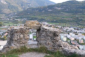 Small stone wall partially destroyed. In the centre of the wall is a hole.