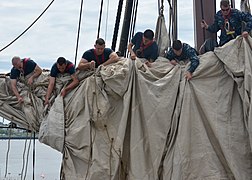 Marins de l'US Navy ferlant une voile.