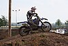 A man riding a motorcycle going up a motocross hill near the peak