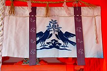 A hanging fabric at Kumano Nachi Taisha, depicting two three-legged crows holding a plant.