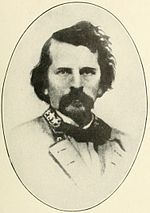 Sepia print of a dark-haired man with a large moustache. He has a general's stars on his collar.