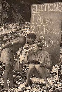 sitting man receiving an oral vote from a voter during a local council election