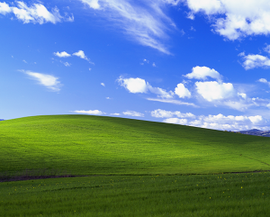 A rolling green hill and a blue sky with stratocumulus and cirrus clouds