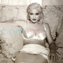 Madonna in a white dress sitting on a sofa and smiling