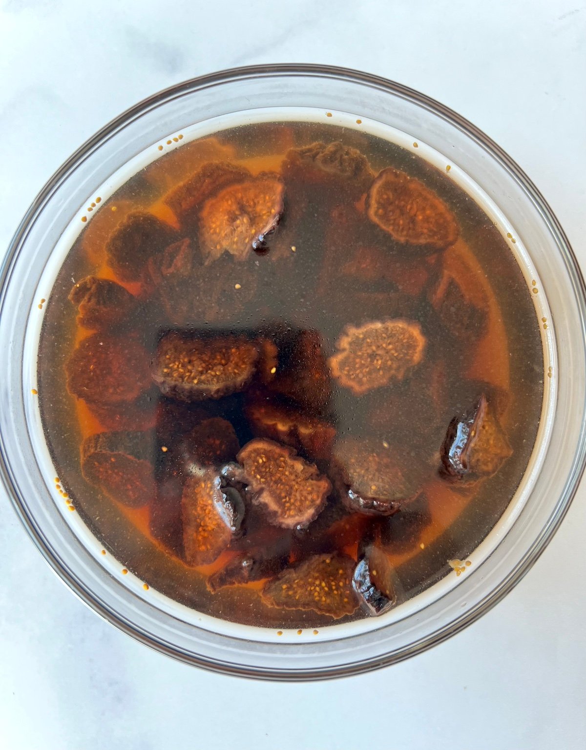 Dried figs soaking in bowl of warm water.