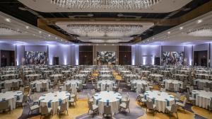 Wide view of several tables in the event space highlighted by white lights