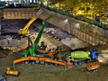 Photo showing a concrete pump working a large foundation pour, showing deployed outriggers, rebar mats, and concrete mixer delivering concrete.