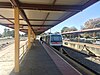 Train stopped at concrete platform with shelter running along the platform