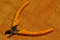 Light-duty flush cutting wire cutters with offcut retaining finger