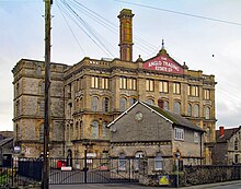 Four storey building with chimney behind gates and walls.