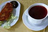 Borscht sprinkled with parsley, served with a dollop of sour cream and a slice of rye bread