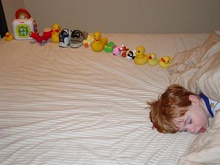 Sleeping boy beside a dozen or so toys arranged in a line