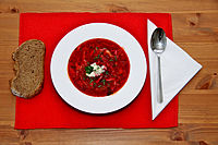 Borscht sprinkled with parsley, served with a dollop of sour cream and a slice of rye bread