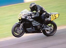 Black motorcycle racing at a non-street circuit with rider also wearing black