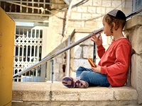 A haredi boy eats a sufganiyah in the old city of Safed.