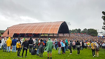 The Alpha is the largest stage at Lowlands festival, with a capacity of 15,000 attendees. It succeeded the "Hoofdpodium" (main stage) in 1993. The blue and yellow striped circus tent (on the left) was replaced in 2017 by a higher, more open tent with arched roof (on the right).[23]